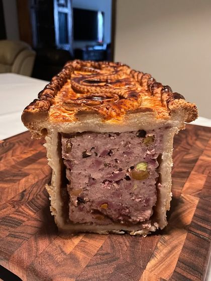 A cross-section of my Pâté En Croute. This intricate meat pie is a labor of love, featuring lamb, poultry, and pork with Armagnac-soaked prunes, all wrapped in a duck fat pastry.