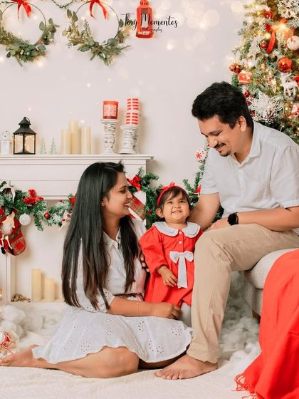 Sharing a sweet moment as a family. The festive decor and their loving interaction make this a heartwarming photo, perfect for remembering their baby's first Christmas.