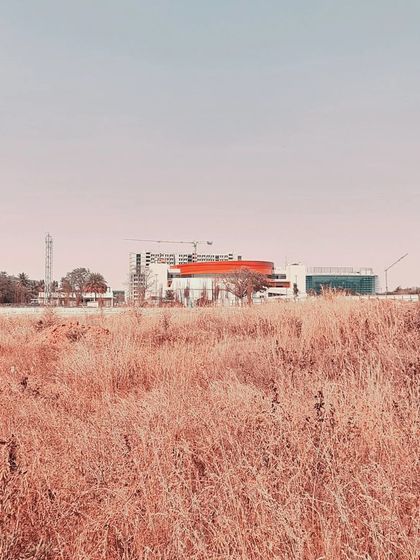 A distant, atmospheric shot of the MARC Auditorium under construction, emphasizing its distinctive form against the sky.