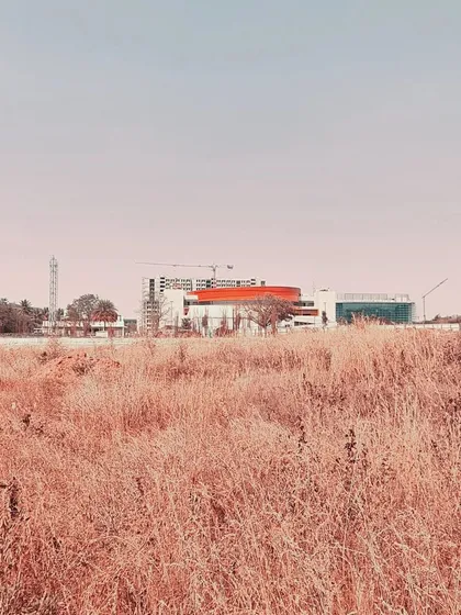 A distant, atmospheric shot of the MARC Auditorium under construction, emphasizing its distinctive form against the sky.