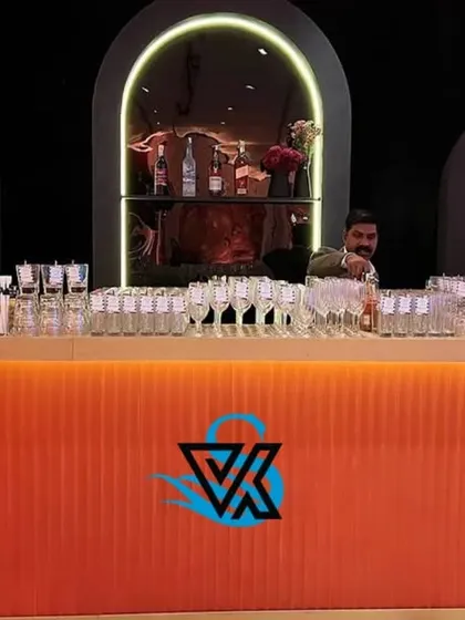 A straight-on shot of the modern orange and black bar, fully stocked and ready for the party. The clean lines and bold colors make it a central feature of the event design.