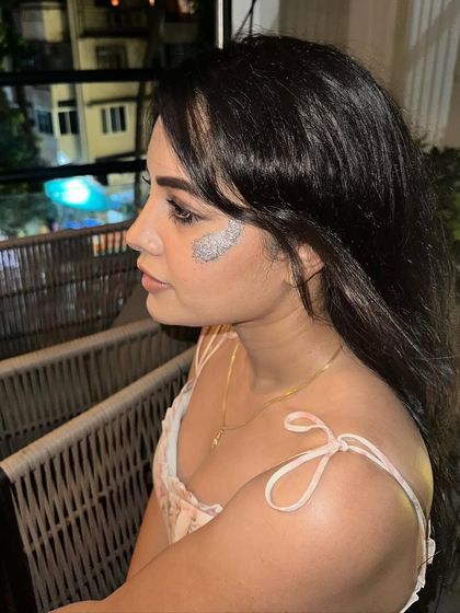 A side profile of a silver glitter design on the cheek. The chunky glitter pieces create a beautiful, textured sparkle.