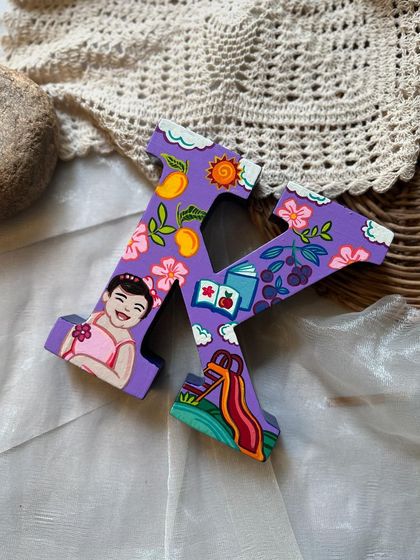 We created this personalized alphabet "K" for Dimple's daughter, Kaira. The letter is decorated with illustrations of all her favorite things, like slides, books, and mangoes.