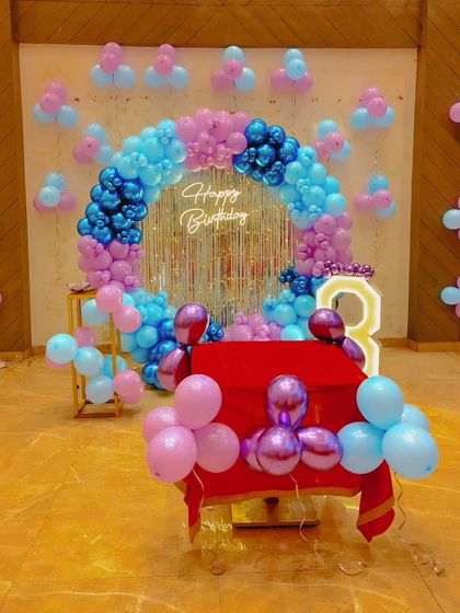 A pink and blue themed birthday setup with a circular balloon arch, a shimmer wall backdrop, and a light-up number '3'. This color combination is great for many themes.