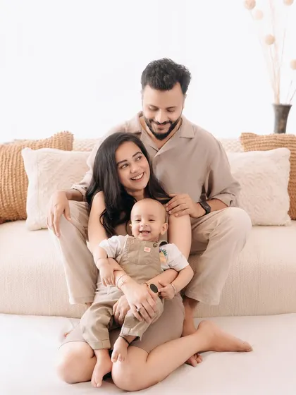 A beautiful family of three sharing a happy moment. The baby's joyful expression is the centerpiece of this warm and loving studio portrait.
