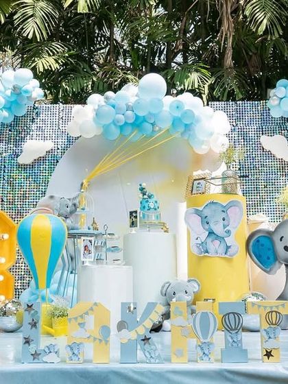 The full view of the baby elephant themed birthday bash. The balloon arch in pastel blue and yellow frames the scene perfectly, creating a beautiful and inviting space for a third birthday celebration.
