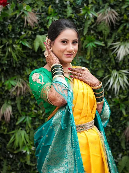 A close-up of the bride, her hands framing her face. The makeup is soft and natural, with a focus on her glowing skin.