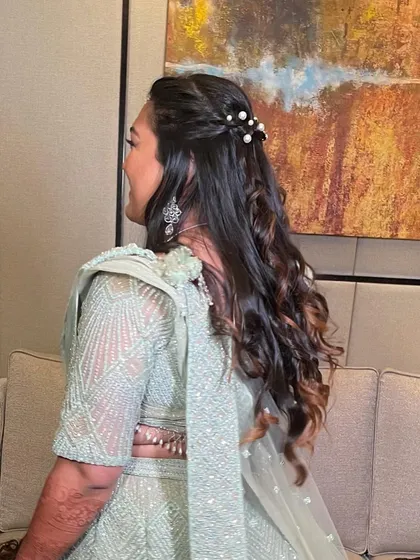 A side view of the half-updo with pearls, showing the soft texture of the curls.