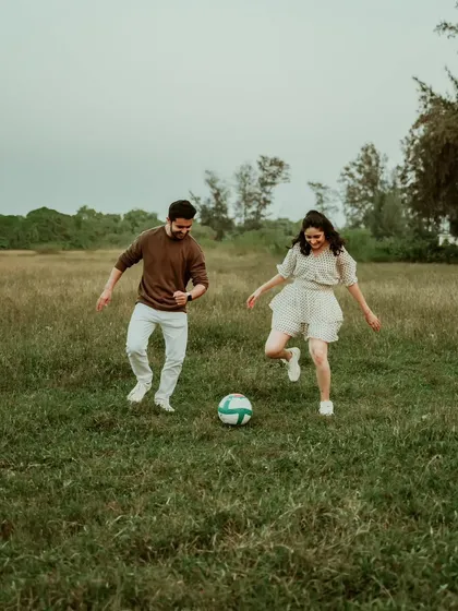 A playful moment of a couple kicking a football around in a grassy field in Mumbai. This candid shot shows that pre-wedding sessions can be relaxed, fun, and full of personality.