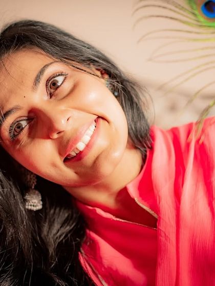 A fun and expressive portrait. The wide smile and playful use of the peacock feather create a joyful and energetic shot.