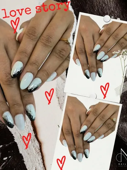 A modern black and white set with a touch of sparkle. This design features a black glitter fade over a clean white base on almond-shaped nails.