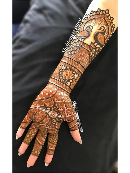 An engagement design with two peacocks perched on an arch. This creates a beautiful and regal frame on the back of the arm.