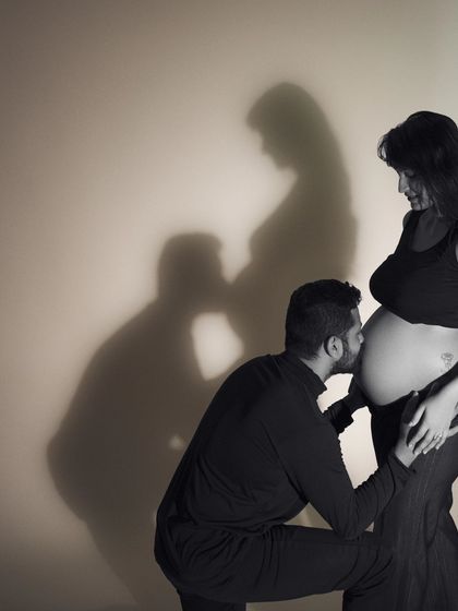 Love in bloom. In this tender moment, love and anticipation entwine as a father-to-be showers love on the precious baby bump, captured with a creative shadow effect.