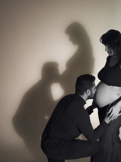 A kiss in the shadows. This creative silhouette uses shadows to mirror the couple's pose, adding an artistic and conceptual layer to a tender moment. It’s a visual representation of their two hearts becoming three.