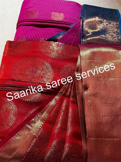 A red and a pink saree, both with rich gold work, ready for a customer.