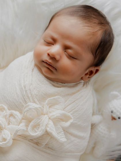 A detailed close-up on the newborn's peaceful face, highlighting the delicate features and soft textures of the swaddle.