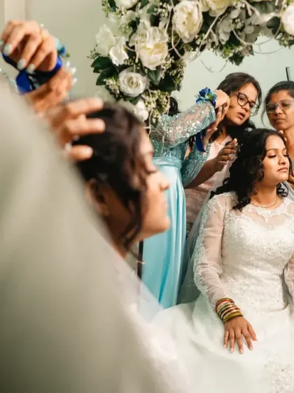 A view from over the hairstylist's shoulder, capturing the bride's reflection as her team works on her final look.