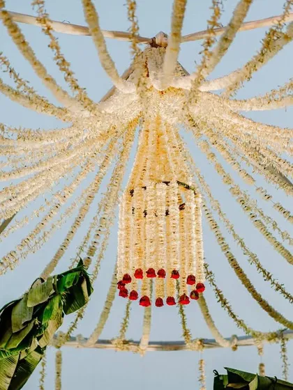 A view from under the canopy of the minimal mandap, showing the intricate floral chandelier made of mogra and rose garlands. This detail adds a touch of luxury to the simple design.