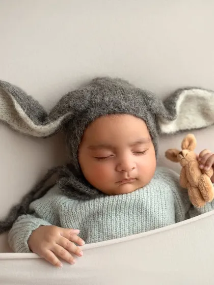 Even simple props can be so effective. Here, a cozy bunny hat adds a touch of whimsy to this portrait of a sleeping twin, showing how accessories can enhance a newborn photo.