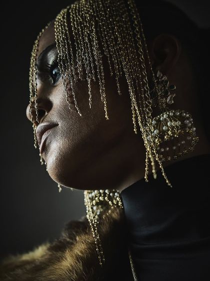 A close-up profile shot for Reasons Jewellery, highlighting an elaborate chain headpiece and large pearl earrings with dramatic, shadowy lighting.