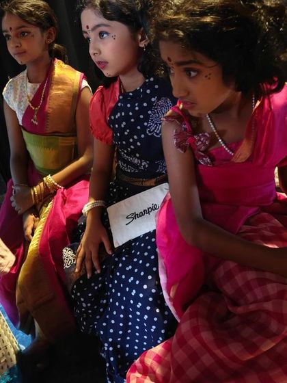 A duplicate of the backstage moment, highlighting the beautiful costumes and the quiet concentration of the performers before they go on stage.
