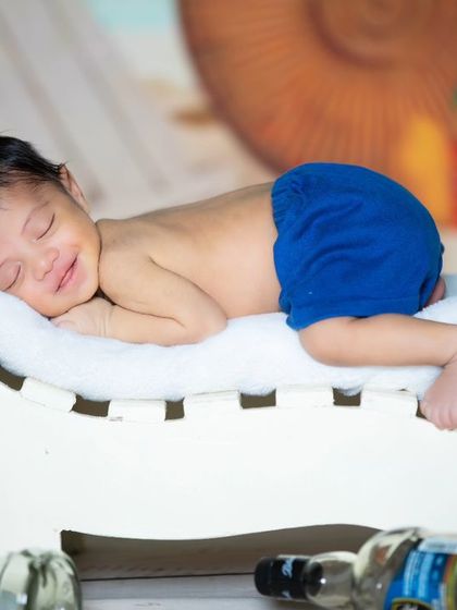 This baby is enjoying a nap on a beach lounge chair, surrounded by empty beer bottles for a humorous touch.