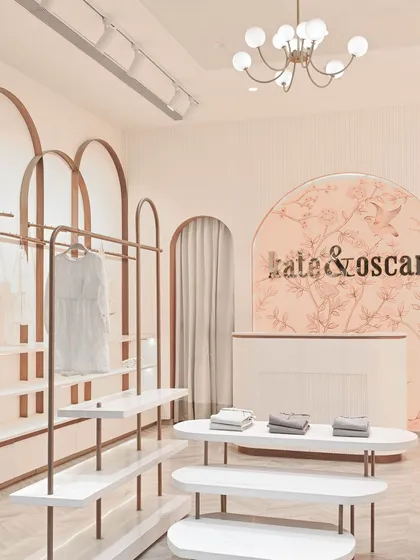 The central display tables are designed with soft, rounded shapes and rose gold legs, continuing the store's gentle and elegant aesthetic.
