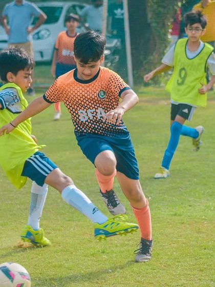 A player in an orange jersey attempts to tackle an opponent, showcasing defensive skills and determination.