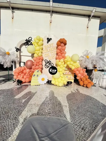 A look at our "Sweet as Can Bee" theme in action on a sunny rooftop. This setup features a vibrant balloon garland in shades of yellow and peach, oversized daisies, and adorable bee accents for a cheerful and playful baby shower celebration.