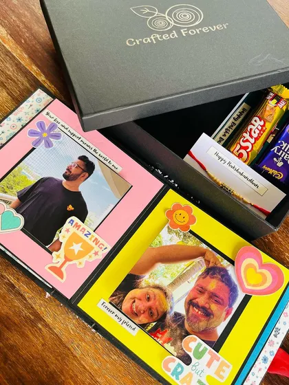 This is one of my favorite Rakhi hampers. It features a personalized scrapbook filled with childhood photos, a bar of chocolate, and a handwritten card, all presented in my signature gift box. It’s the perfect way to send love to your sibling.