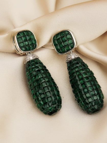 Luxury should look as good as it feels. These carved emerald drop earrings are laid on a bed of champagne-colored silk, a simple setup that exudes sophistication and highlights the product's rich texture.