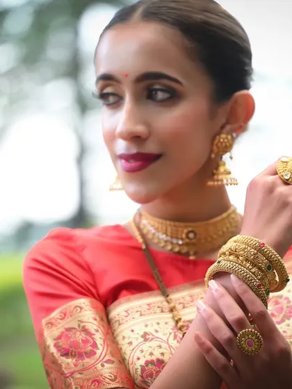 An elegant three-quarter portrait of the model, her pose designed to showcase the full set of traditional gold jewelry.