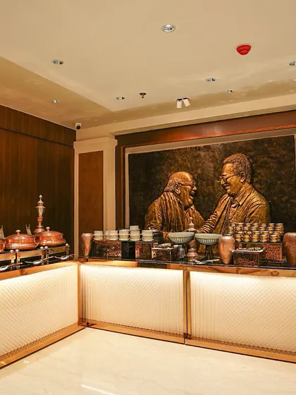 Our catering setup inside a formal, wood-paneled event space. The illuminated buffet counter and copper chafing dishes complement the room's luxurious interior design.