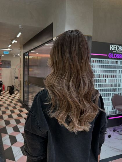 The view from the back shows the full effect of this ash blonde balayage, with a seamless transition from the natural root color to the lightened ends.