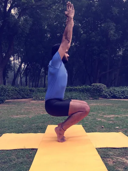 This balancing toe stand, a variation of Utkatasana (Chair Pose), challenges your stability and strengthens your ankles and feet. It teaches you to find your center of gravity and remain steady through focus.