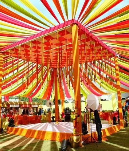A vibrant wedding mandap with a ceiling of multi-colored drapes. This setup is perfect for a lively Haldi or Mehendi ceremony.