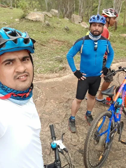 A rider taking a selfie during a break on a forest trail, capturing the rugged terrain.
