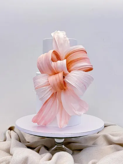 I absolutely love the dramatic and modern look of wafer paper. This two-tiered cake features a large, hand-painted pink bow, showing how a simple, clean design can be transformed into a true statement piece.