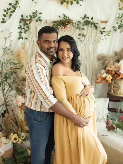 A happy and connected couple's portrait. They embrace warmly, smiling for the camera, perfectly capturing the joy of their pregnancy journey in a relaxed setting.