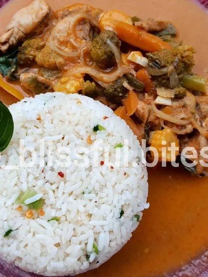 My homemade Thai Red Curry with vegetables and chicken, served with a side of perfectly molded herbed garlic rice. A complete and flavourful meal in a bowl.