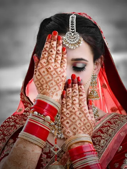 The beauty of a bride is in the details. This portrait highlights the intricate mehndi design, a symbol of love and celebration, while capturing the bride's shy glance.