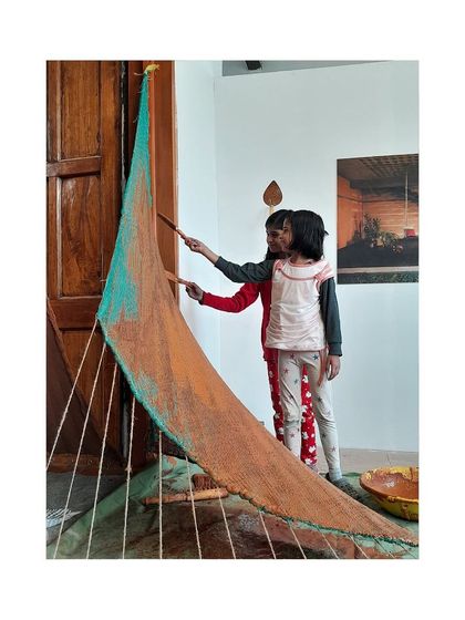 Even our youngest visitors get involved. Here, children are guided to apply mud plaster to the installation, making art and learning about sustainable materials.