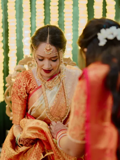 A quiet moment during the ceremony. The bold red lip stands out beautifully against the off-white and red Kanjivaram saree, creating a classic and timeless bridal look.