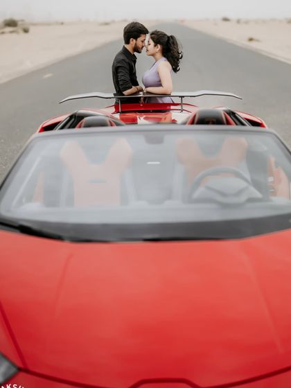 A romantic shot of the couple looking into each other's eyes, framed by the windshield of the sports car.