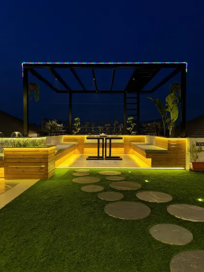 The same modern black pergola at night, with integrated lighting that transforms it into a dramatic and inviting space. The multi-colored RGB lights on the frame add a fun, customizable element.