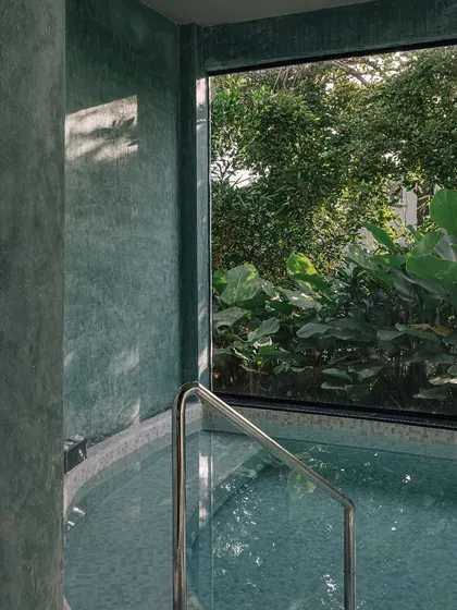 The indoor jacuzzi at the Aqua spa, featuring textured green walls and a large picture window that looks out onto dense foliage, creating a private and immersive wellness experience.