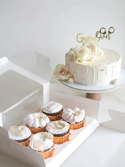 This elegant white drip cake, adorned with fresh roses and a playful "Game Over" topper, was created for a bachelorette party. It was part of a special order that also included custom cupcakes.