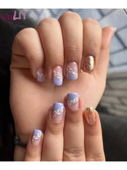 Lilac love. This pretty manicure combines solid lilac nails with accent nails featuring a simple white leaf design and a touch of gold glitter.