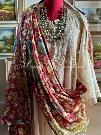 A truly regal statement, this Chikankari tissue chanderi Anarkali is draped with a magnificent Srikalahasti Kalamkari dupatta. The hand-painted peacock motifs on a deep maroon base evoke a sense of heritage and grandeur, perfect for the most special occasions.