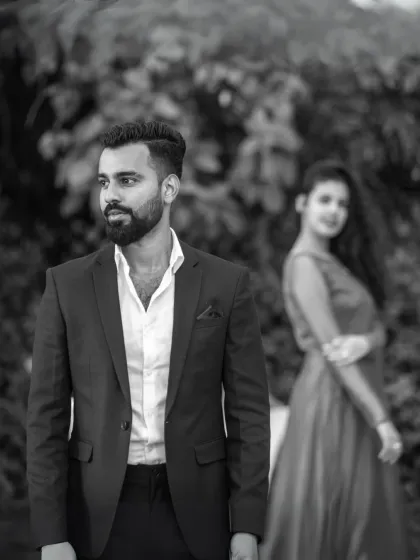 A classic black and white portrait that emphasizes emotion. The focus on the groom with the bride softly in the background creates a thoughtful and artistic composition.